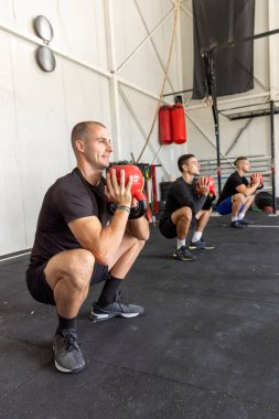 Spor salonunda spor grubu halteri kaldırıyor.