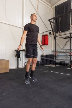 Spor salonunda ip atlayan bir adam.