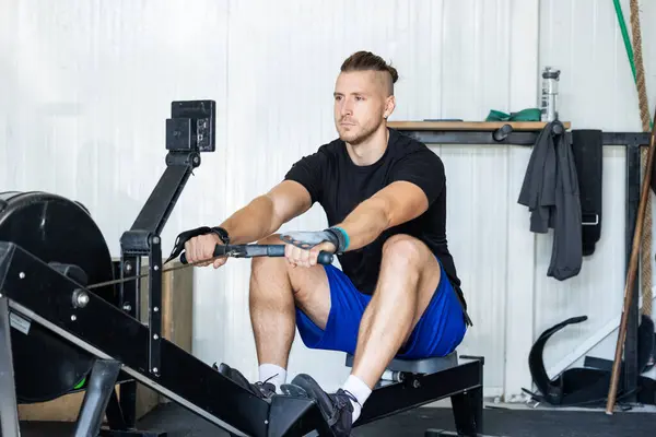 Fitness man on rowing machine doing exercises