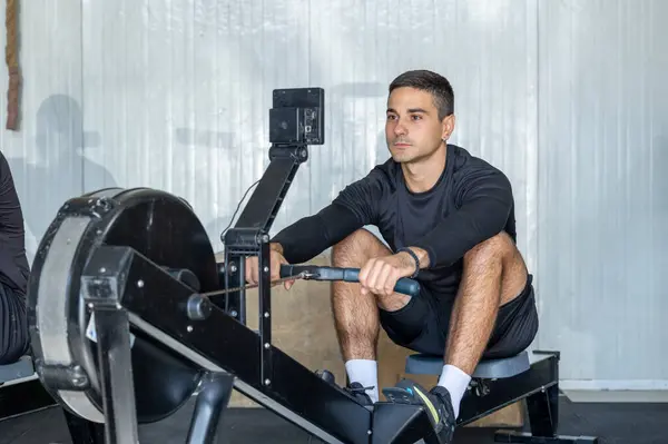 Spor Yapan Adam Kürek Makinesinde Egzersiz Yapıyor - Stok İmaj