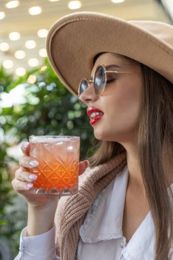 Güzel genç bayan restoranda tek başına kokteyl içiyor.