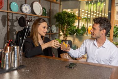 Mutlu çift açık hava bahçe restoranında kokteyllerle kadeh kaldırıyor.