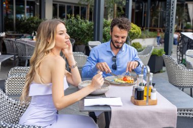 Restoran bahçesinde romantik bir akşam yemeği yiyen yakışıklı çift.