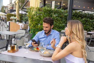 Restoran bahçesinde romantik bir akşam yemeği yiyen yakışıklı çift.