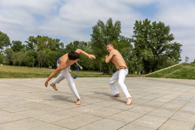 Genç ve orta yaşlı bir adam Capoeira, Brezilya dövüş sanatları eğitimi alıyor.