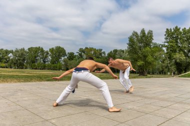 Teenager and middle aged man practicing capoeira , brazilian martial art