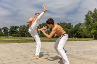 Teenager and middle aged man practicing capoeira , brazilian martial art