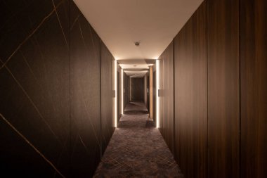 Ahşap duvarları olan uzun bir otel koridorunun içi.