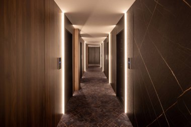 Ahşap duvarları olan uzun bir otel koridorunun içi.