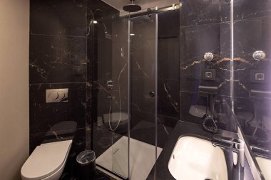 İçinde mermer duvarlar ve cam duş kabini olan lüks bir otel banyosu.