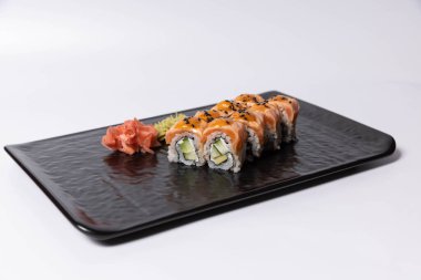 Siyah bir taşta servis edilen somon derisi suşi rulosu.