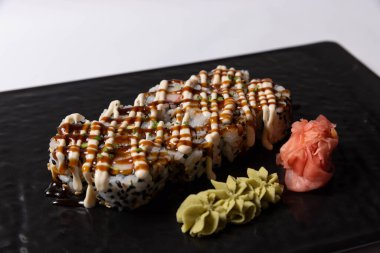 Somon derisi suşi rulosu, siyah bir taşın üstünde servis edilir.