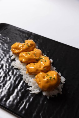 Somon derisi suşi rulosu, siyah bir taşın üstünde servis edilir.