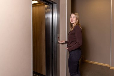 Mutlu genç bayan asansöre biner ve arkadaşını arar.