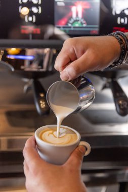 Profesyonel barmen kafe barında mükemmel bir kapuçino hazırlıyor.