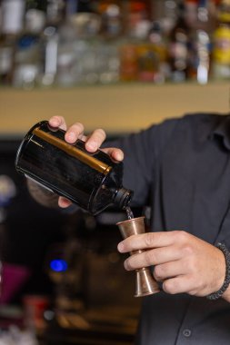 Barmen kokteyl için içkiyi ölçüyor..