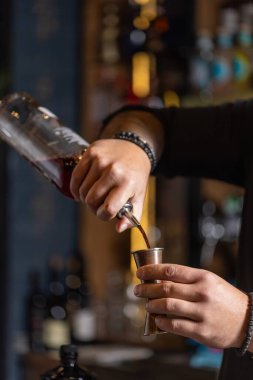 Barmen kokteyl için içkiyi ölçüyor..