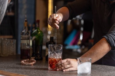 Barmen bardakta alkol kokteyli hazırlıyor.