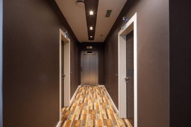 Uzun bir otel koridoru, kapı aralığı.