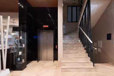 Asansörü ve merdivenleri olan modern otel lobisi.