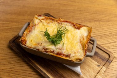 Tahtadaki seramik kasede servis edilen lazanya.