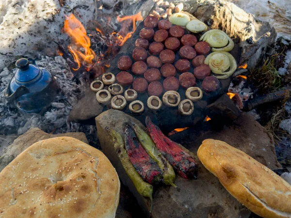 Camping meal preparation over wood fire and count stone