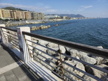 Arka planda çit ve deniz olan bir gezinti alanı.