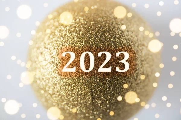 stock image Happy new year! New year of 2023 concept. Year number on gold color glitter Christmas bauble. Indoors, studio shot.