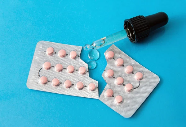 Taking CBD oil together with birth control pills could disrupt hormones and reduce birth control pills effectiveness and result in unwanted pregnancy. CBD oil, birth control pills on blue background.