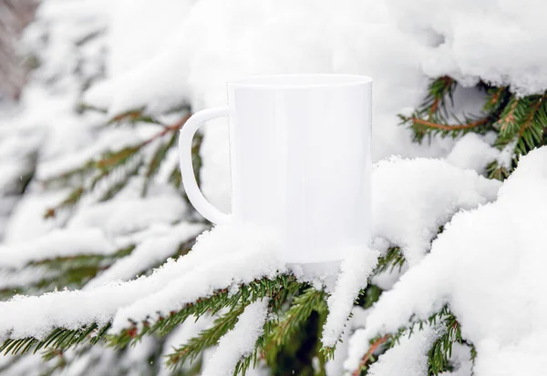 White blank coffee mug mock up template. Cozy seasonal products advertisement background. Single cup on snowy Scandinavian winter nature background. Room for text.