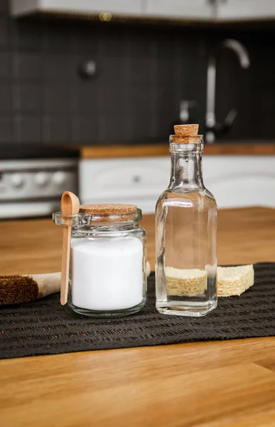 Using baking soda Sodium bicarbonate and white vinegar for home kitchen cleaning concept. White vinegar in glass bottle and baking soda in glass jar.