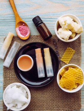 Ev yapımı dudak kremi: Shea yağı, gerekli yağ, mineral rengi pudrası, balmumu, hindistan cevizi yağı. Ev yapımı dudak nemlendirici ruj. Masadaki malzemelerle karıştırılmış..