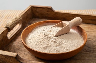 Evde ahşap kase ve kaşık üzerinde psilyum kabuğu un tozu. Psyllium un konseptinin sağlık faydaları.