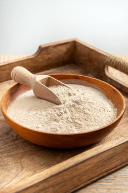 Evde ahşap kase ve kaşık üzerinde psilyum kabuğu un tozu. Psyllium un konseptinin sağlık faydaları.
