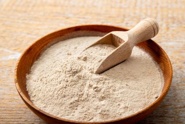 Evde ahşap kase ve kaşık üzerinde psilyum kabuğu un tozu. Psyllium un konseptinin sağlık faydaları.