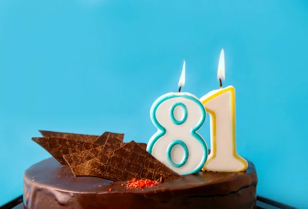 Number 81 birthday candle burning on cake. The eighty-one birthday or anniversary celebration concept. Lot of copy space on blue background.
