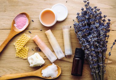 Ev yapımı ruj için malzemeler: Shea yağı, gerekli yağ, mineral rengi pudrası, balmumu, hindistan cevizi yağı. Ev yapımı dudak nemlendirici ruj karışımı ve masa içerisindeki malzemeler. Görünümün üstünde.