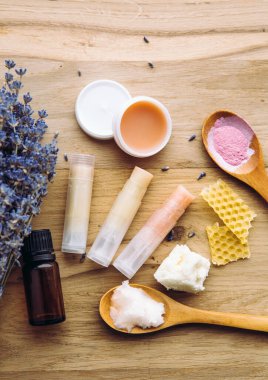 Ev yapımı ruj için malzemeler: Shea yağı, gerekli yağ, mineral rengi pudrası, balmumu, hindistan cevizi yağı. Ev yapımı dudak nemlendirici ruj karışımı ve masa içerisindeki malzemeler. Görünümün üstünde.