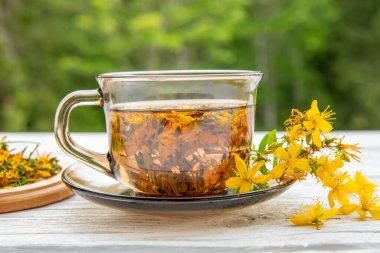 Hiperikum perforatum St John 's wort olarak bilinir, St John' s wort veya yaygın St John bitki çayı beyaz ahşap arka planda cam..