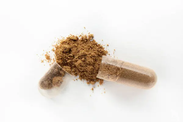 stock image Macro photo of the open capsule with brown powder isolated on white background copy space for text. 