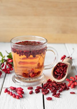 Berberis vulgaris ayrıca ev mutfağındaki sınıf bardağında sıradan böğürtlen, Avrupa böğürtlen ya da böğürtlen çayı olarak da bilinir. Tahta arka planda kurumuş ve taze böğürtlenler..