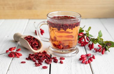 Berberis vulgaris ayrıca ev mutfağındaki sınıf bardağında sıradan böğürtlen, Avrupa böğürtlen ya da böğürtlen çayı olarak da bilinir. Tahta arka planda kurumuş ve taze böğürtlenler..