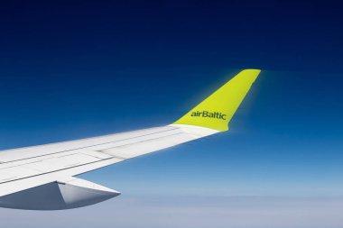 Tallinn, Harjumaa, Estonya-15JUN2023: Uçuş sırasında uçak kanadında AirBaltic tabelası, kabin penceresinden görüntü, pencereden mavi gökyüzü arka plan görüntüsü. Boşluğu kopyala. 