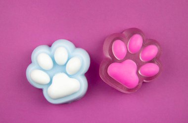 Cute cat paw shape squishy jelly slime toys on purple background, studio shot, copy space. Modern popular sensory toy concept. clipart