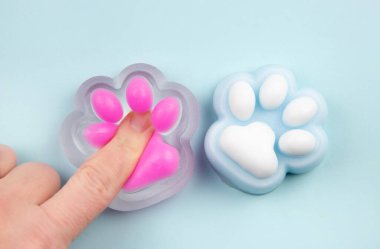 Person finger squeezing cute cat paw shape squishy jelly slime toy, studio shot, copy space. Modern popular sensory toy concept.