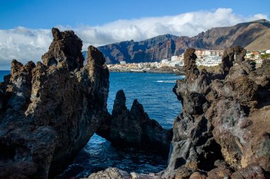 Charco La Vaca, Tenerife, İspanya. Charcos Los Turistas lav kaya oluşumları ve okyanusta mağara ile park ediyor. Uzakta Los Gigantes görüldü.