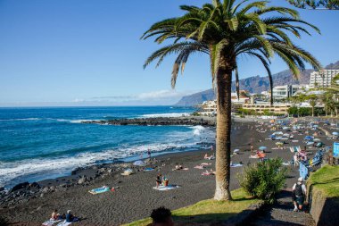 Playa de la Arena, Santa Cruz de Tenerife, İspanya-28JAN2025-Playa de la Arena halk plajı Tenerife Adası, İspanya. İnsanlar güneşleniyor ve güneşli bir günün tadını çıkarıyor..