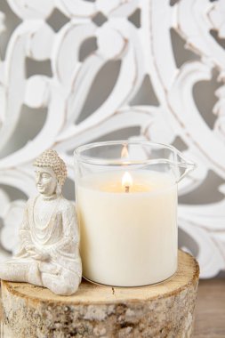 Ev yapımı masaj yağı mumu, cam bardaktan dökülmüş. Bohem tarzı arkaplan, dekorasyon için Buda heykelciği oturuyor.