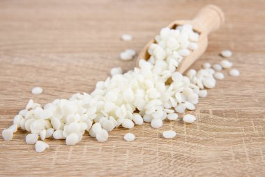 Ahşap kepçe üzerine soya yağı topakları, ahşap masaya saçılmış, stüdyo çekimi, kapalı alan. Mum yapımı için sürdürülebilir temiz malzeme.