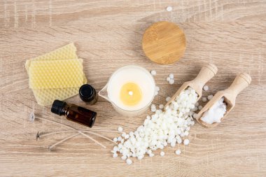 Ev yapımı kokulu masaj yağı mumu yapma kavramı. Aletler, masa kokusu yağ şişelerindeki malzemeler, bardaktan boşaltılmış cam kavanoz, hindistan cevizi cilası, soya cilası taneleri, masada mum fitilleri..